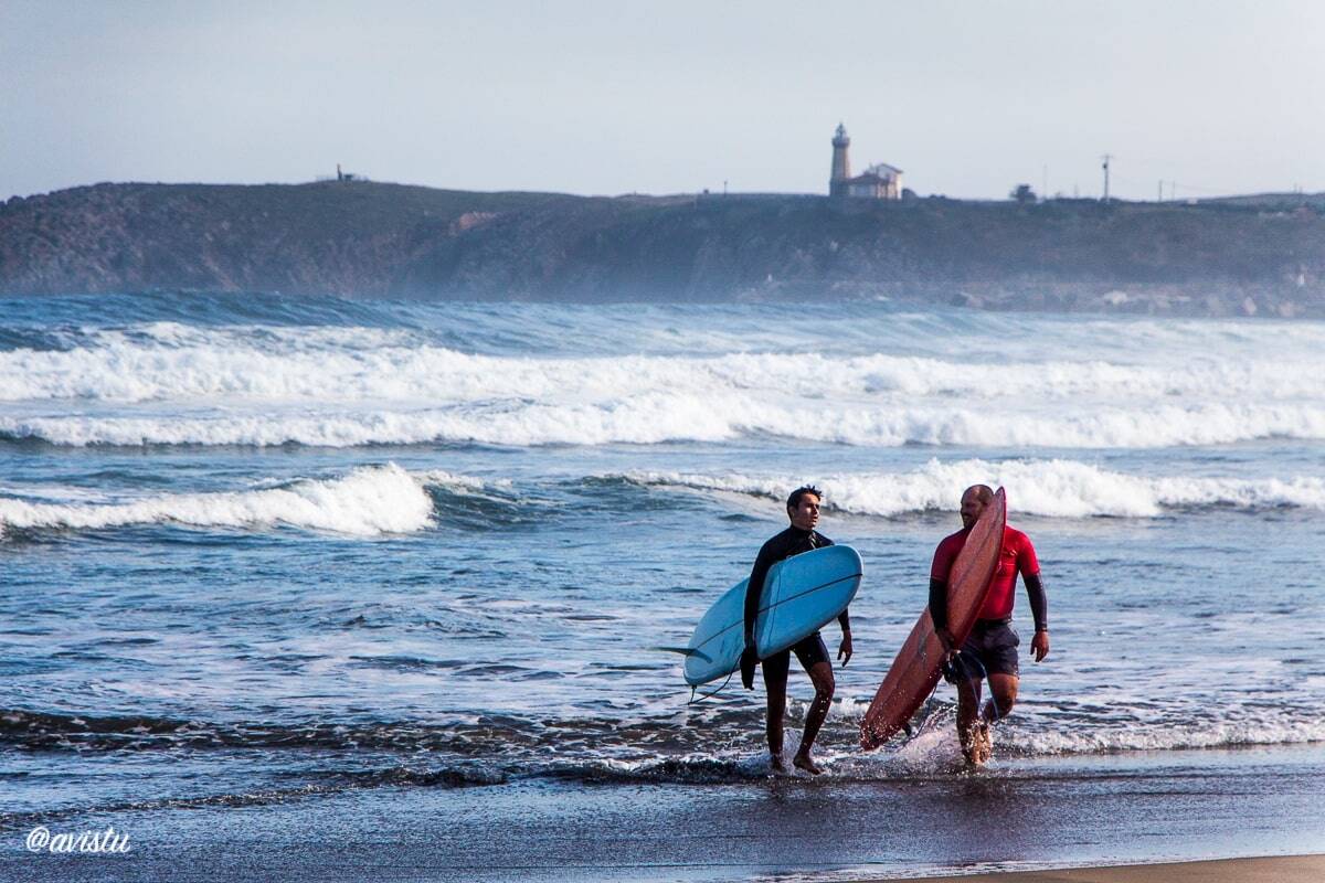 Surferos saliendo del agua en la playa de Salinas (Asturias)