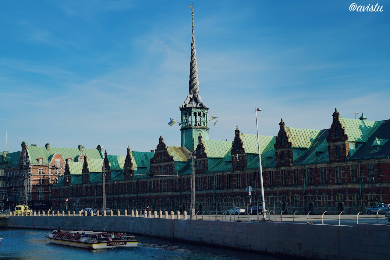 Barco turístico pasando junto al edificio de la antigua Bolsa de Copenhague [(c) Foto: @avistu]