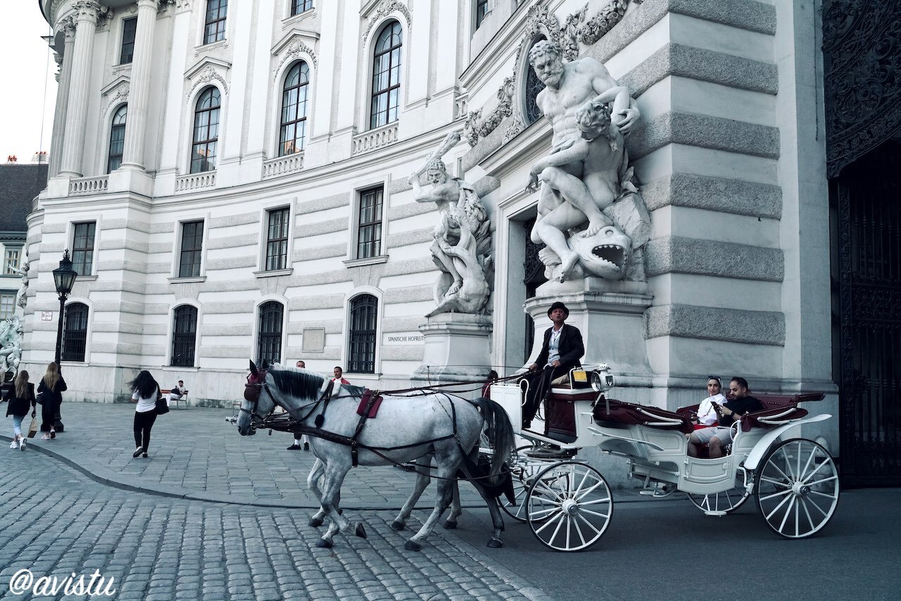 Un Fiaker o carruaje de caballos pasando junto a la Escuela Española de Equitación en Viena [(c) Foto: @avistu]
