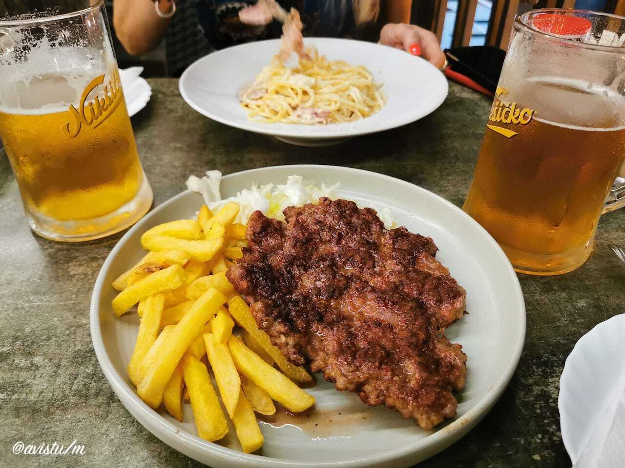 Cenando Pljeskavica, plato nacional en Serbia y alrededores, en un restaurante en Ulcinje, Montenegro [(c)Foto: @avistu]
