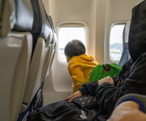 Niño en un avión mirando por la ventana